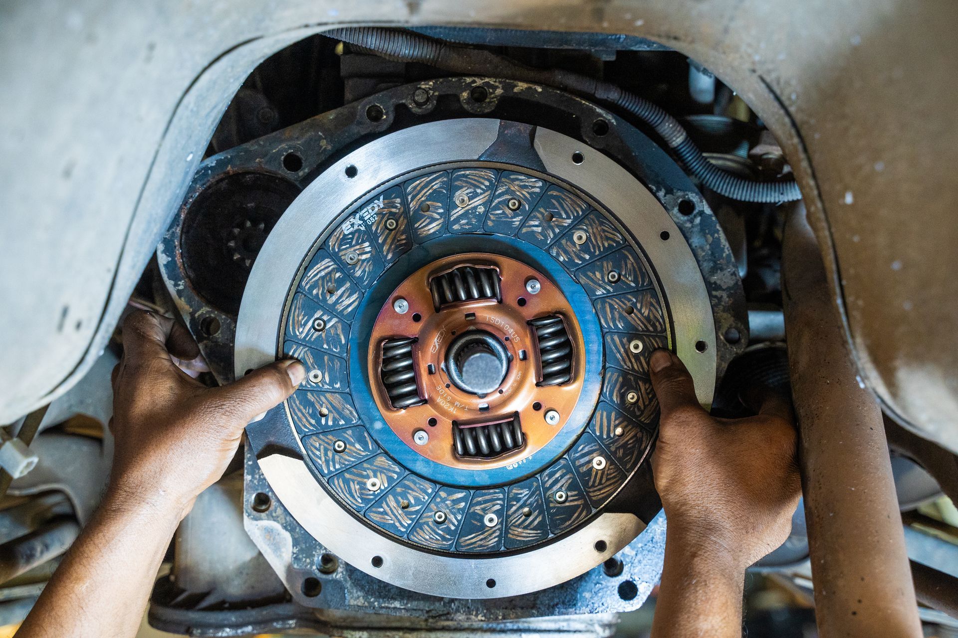 Hands installing a blue-and-orange clutch assembly inside machinery