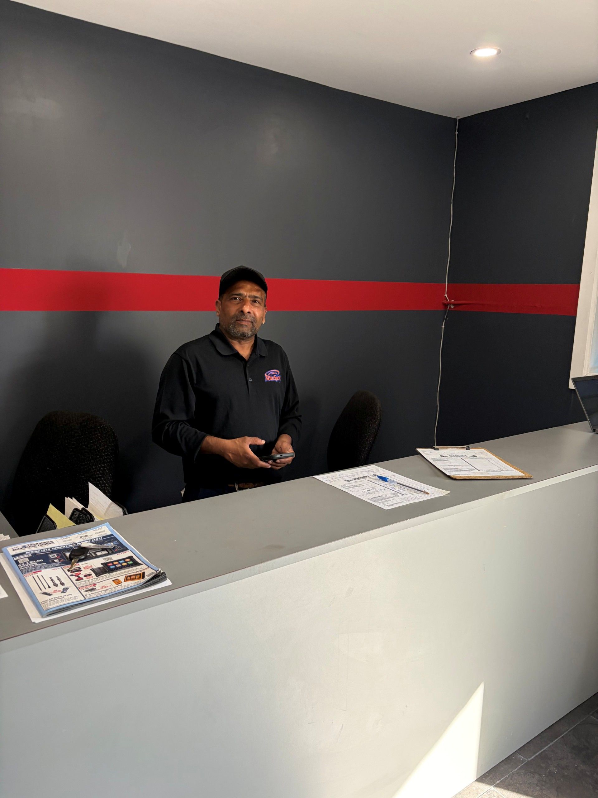 Reception desk with a clerk standing behind a counter in a gray room with a red stripe on the wall.