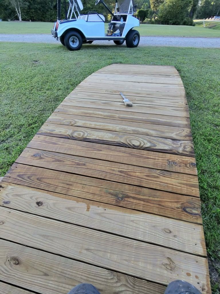 Wooden ramp leading to a white golf cart parked on grass outdoors