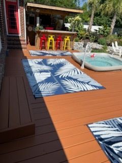 Backyard deck with blue patterned rugs, a small pool, and a colorful bar seating area