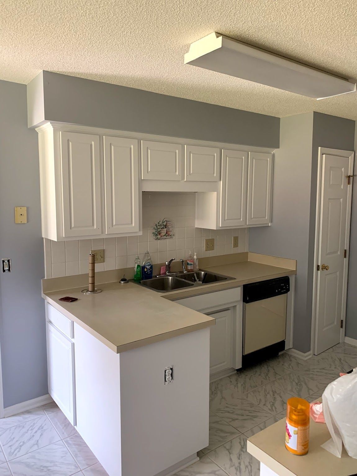 Kitchen with white cabinets, light countertops, and gray walls.