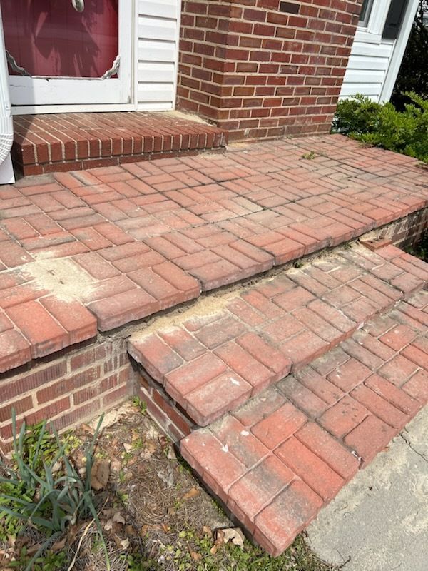 Brick front steps and walkway with a sloped ramp leading to a doorway.