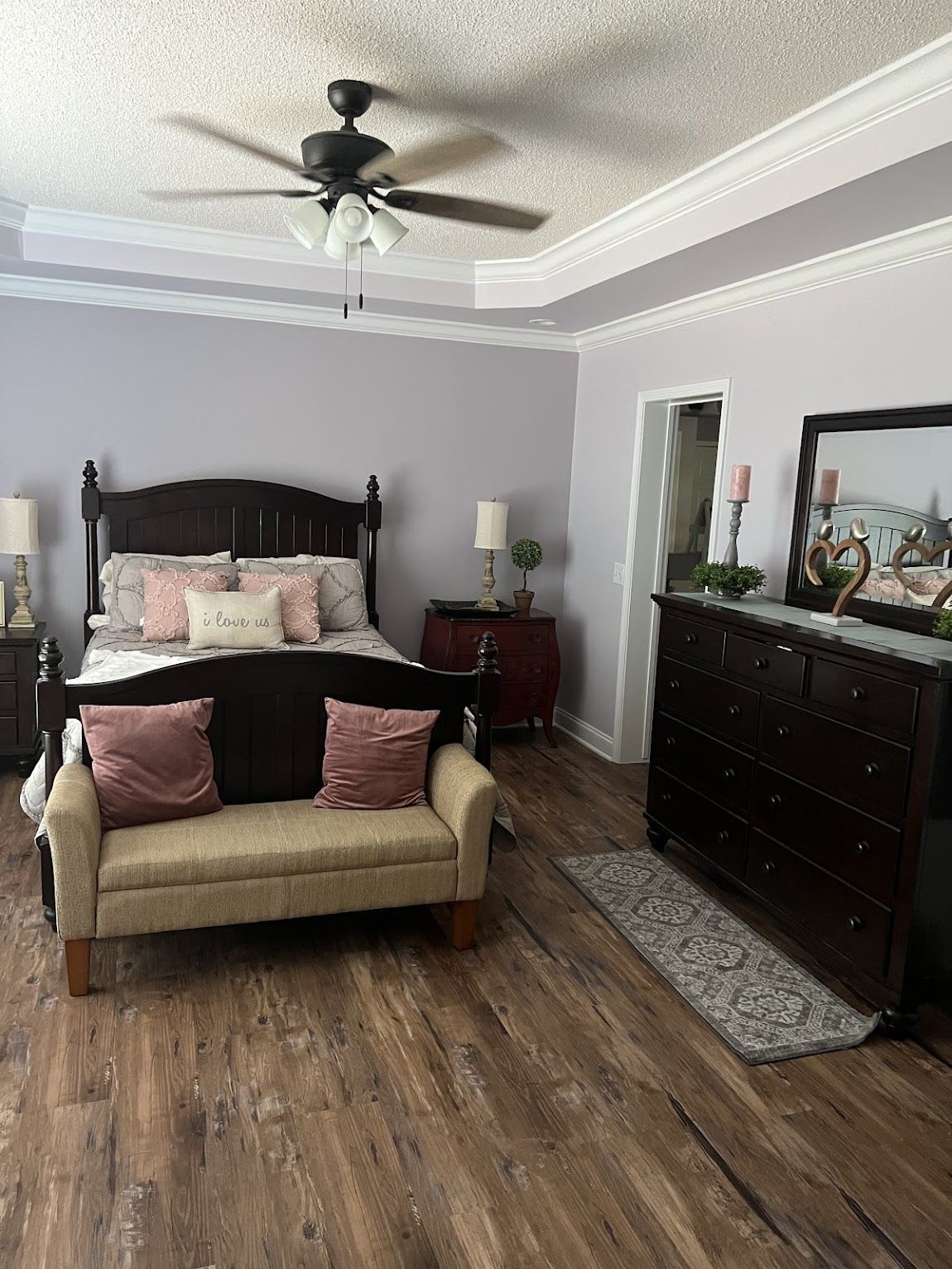 Bedroom with dark furniture, lavender walls, and a light brown floor.
