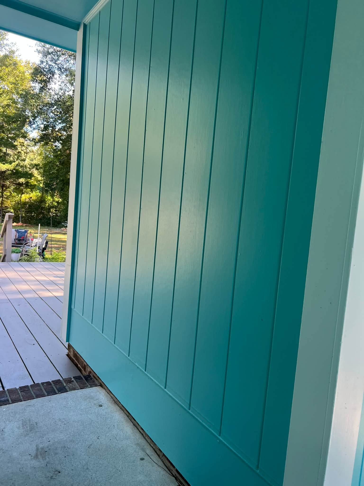 Teal perforated wall beside a sunlit outdoor walkway with trees in the background