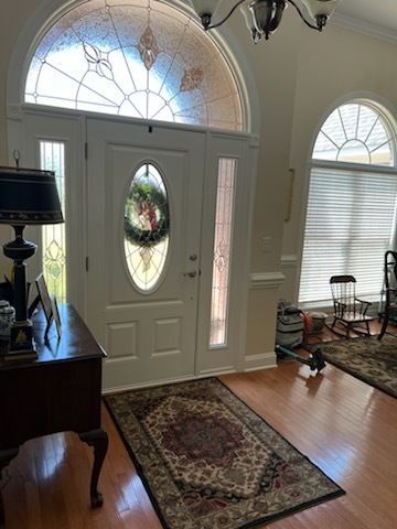 Front entryway with white door, arched windows, rug, and side table in a bright home interior