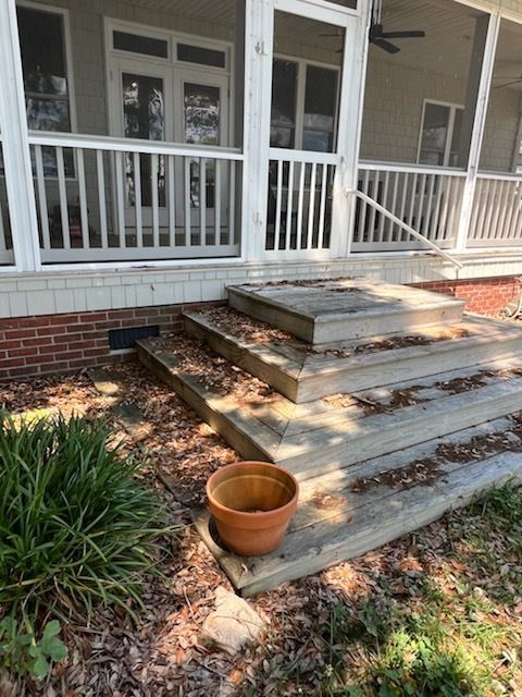 Front porch steps with white railing, red brick base, and a terracotta pot on the ground.