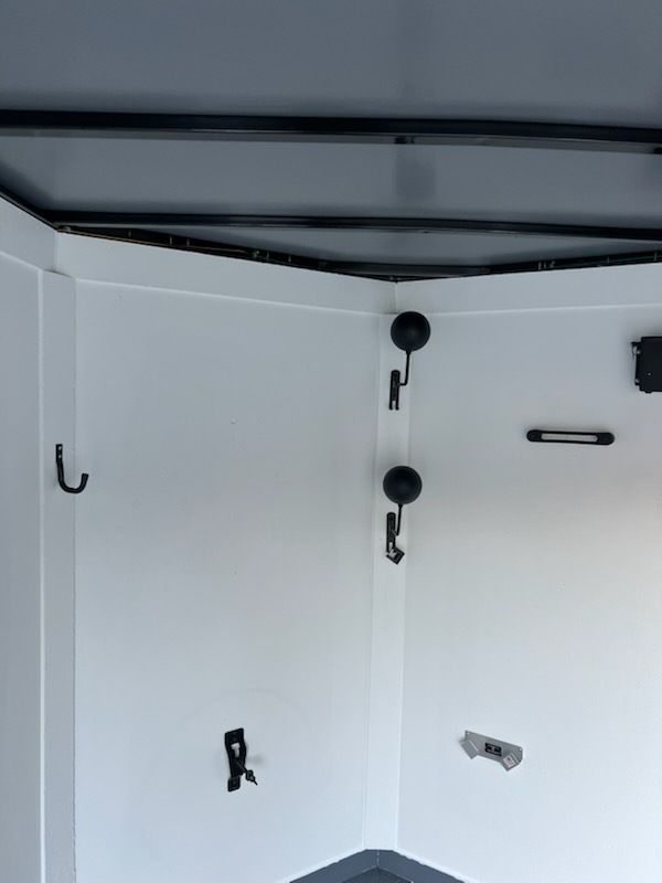 White interior cabinet with hooks, latches, and a metal rod near the ceiling.