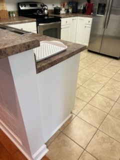 Kitchen with granite counters, white cabinets, stainless fridge, stove, and tiled floor.