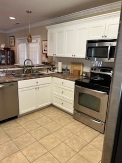 Bright kitchen with white cabinets, stainless steel oven, granite counters, and tan tile floor.