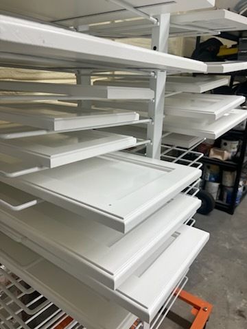 Stacked white shelves in a storage area with metal frames and an orange cart underneath.