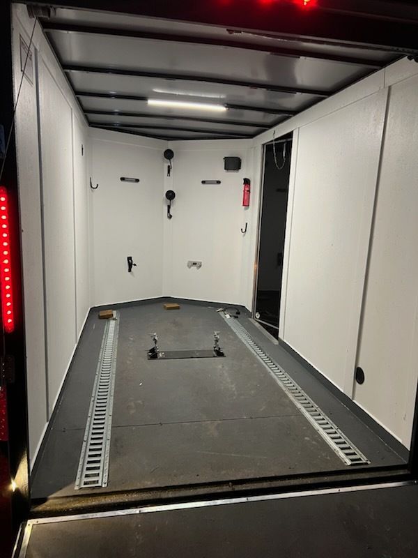 Empty white cargo trailer interior with ramp floor and overhead lights