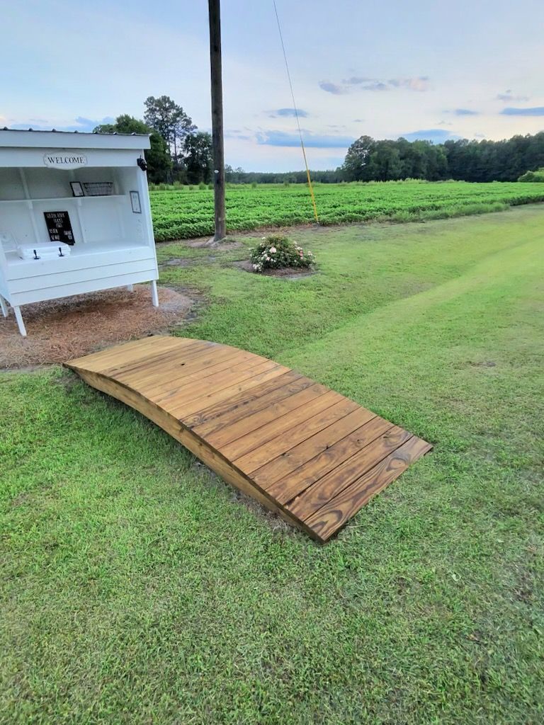 Wooden ramp on grass leading to a small white shed in a rural field
