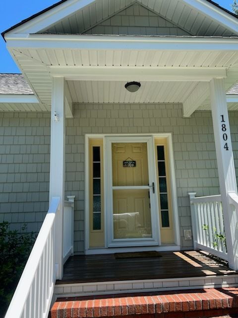 Front porch with white trim, tan front door, and brick steps at house number 1804.