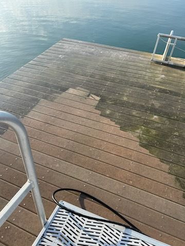 Wooden dock with wet planks beside calm blue water and a metal ladder in the foreground
