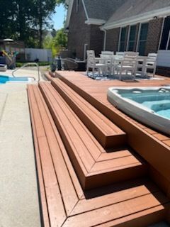 Wooden steps beside a backyard pool and hot tub on a sunny patio