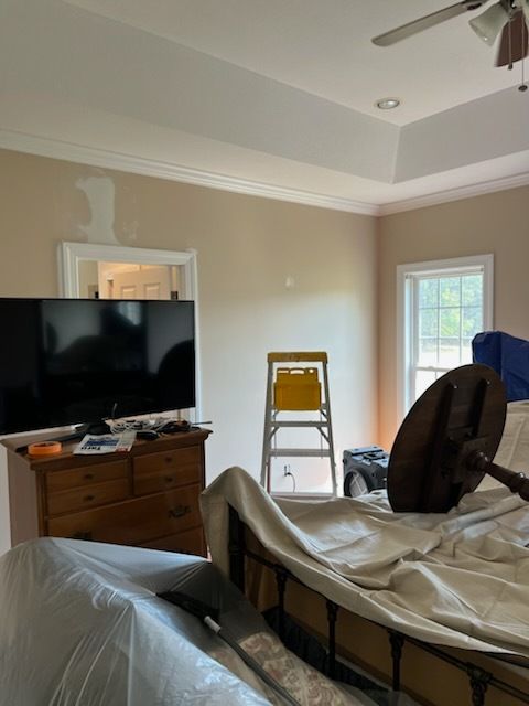 Living room with a TV, dresser, step ladder, and covered furniture during renovation