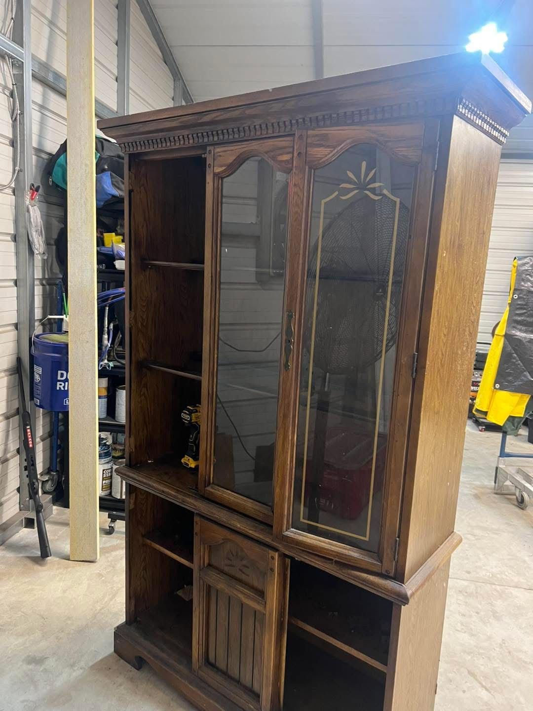 Wooden hutch with glass doors, shelves, and lower cabinet in a workshop setting.