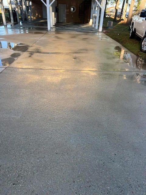 Wet concrete driveway under a covered carport, reflecting light.