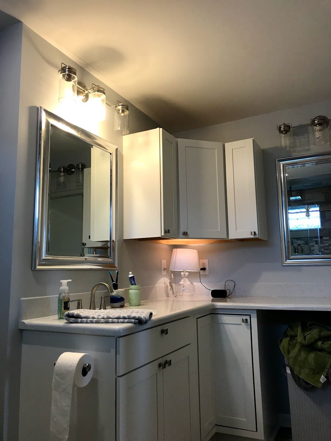 Bathroom with white cabinets, silver-framed mirrors, and bright lighting.