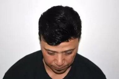 A man in a black shirt is looking down at something.