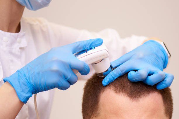 A doctor is examining a man 's hair with a device.