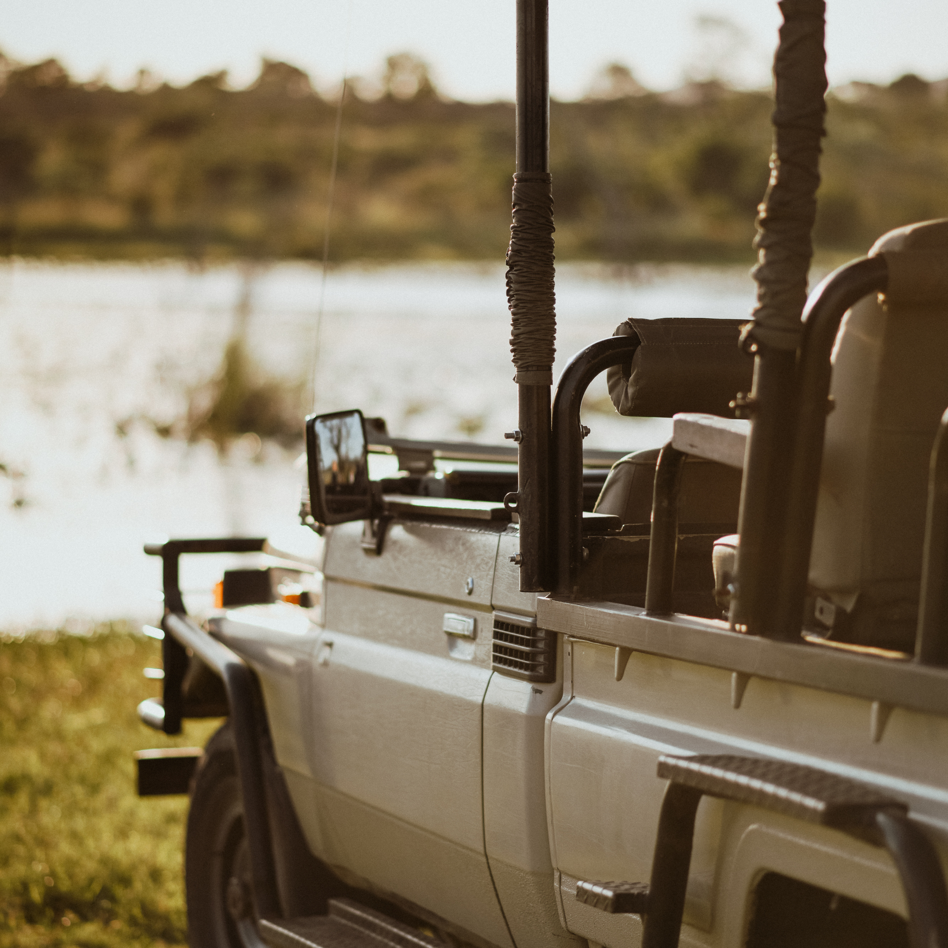 Silver off-road vehicle parked by a lakeside at sunset