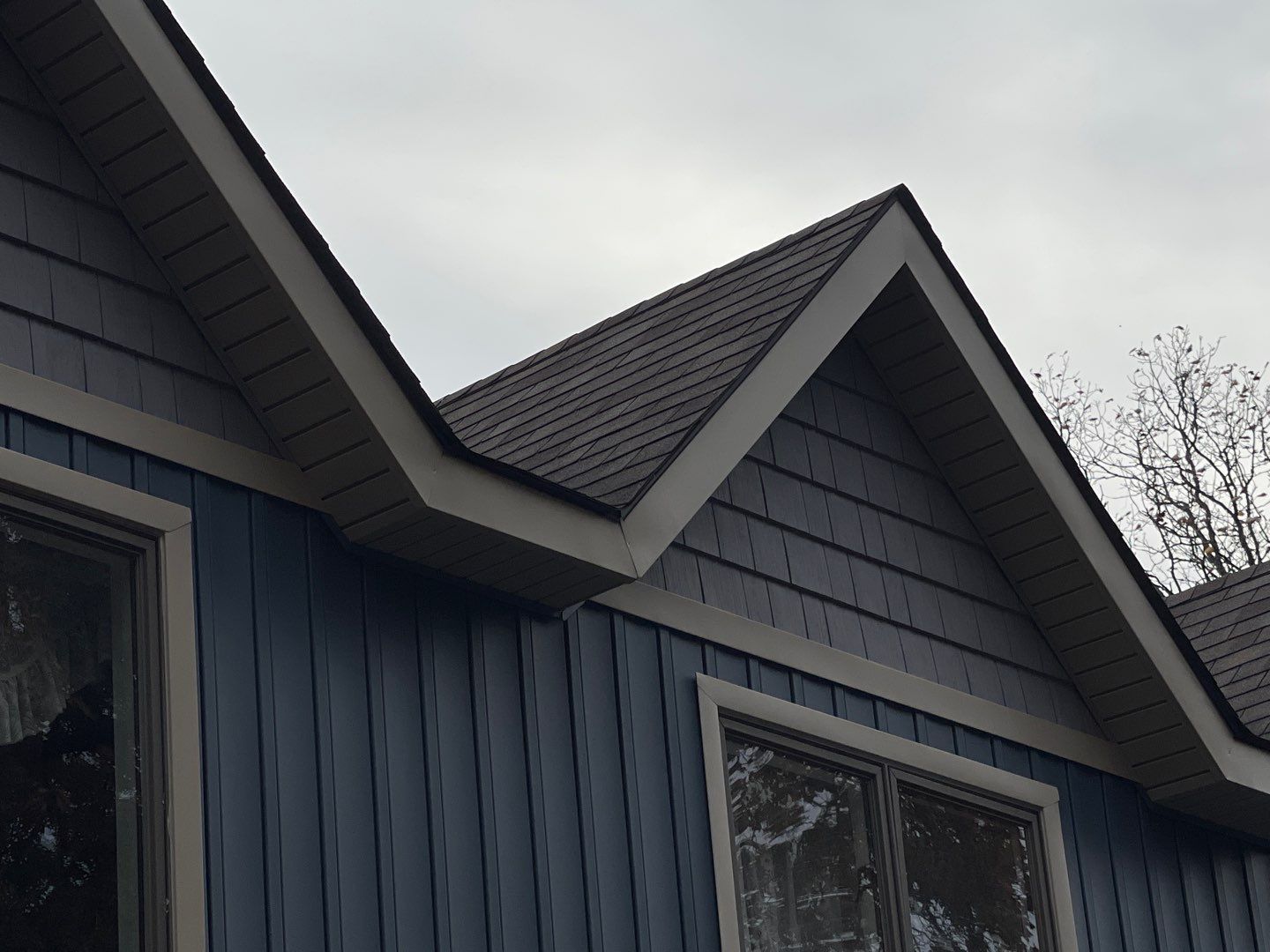 Blue house exterior with dark gray gabled roof and window, viewed from below