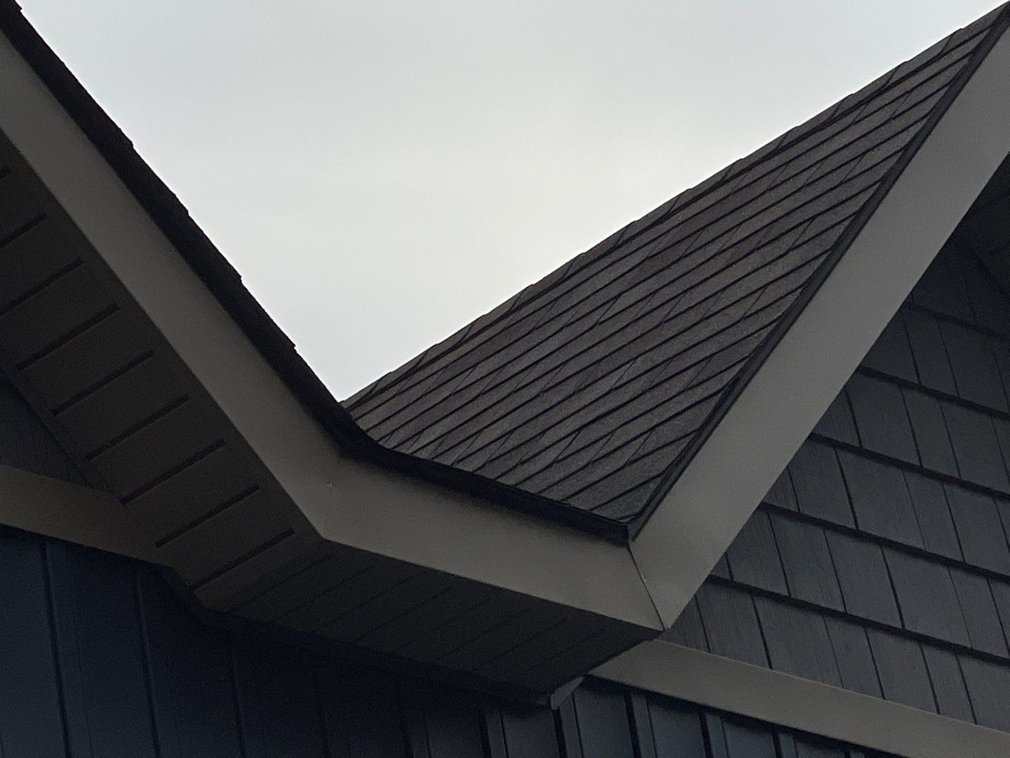 Close-up of a modern house roof with dark shingles and sharp angular gables