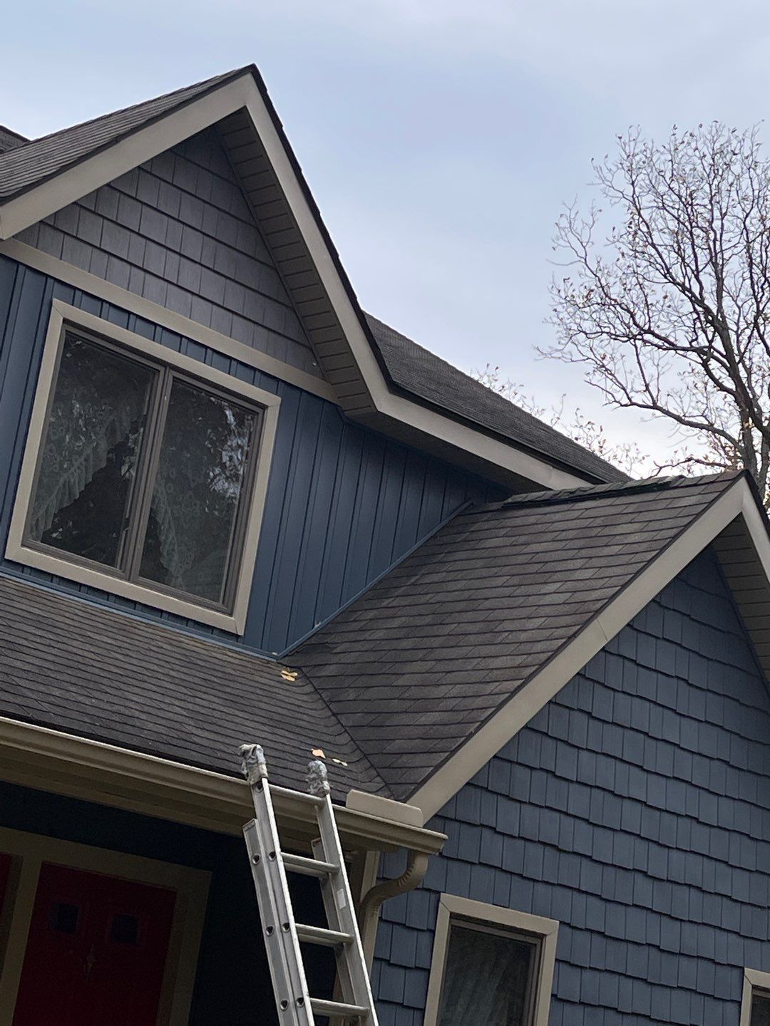 Blue house exterior with a ladder leaning against the roof near a window