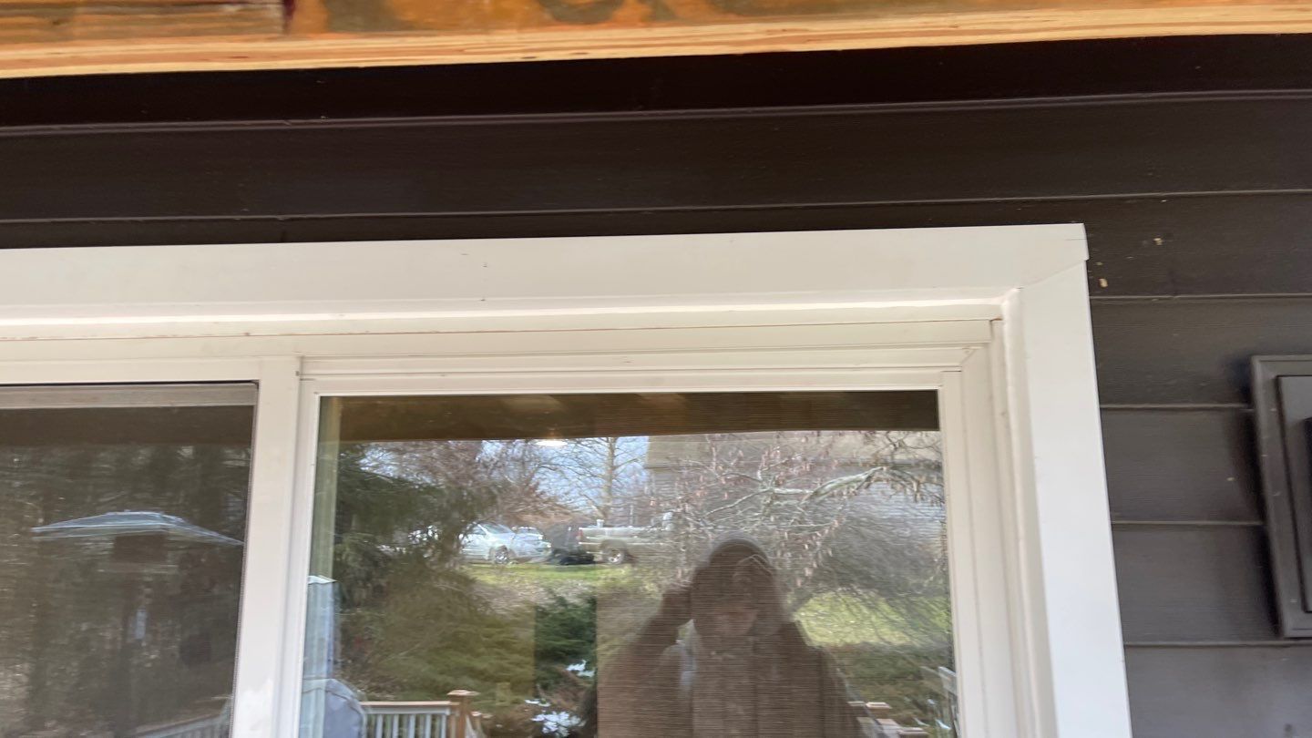 White-trimmed window on a dark exterior wall, with a reflection visible in the glass.