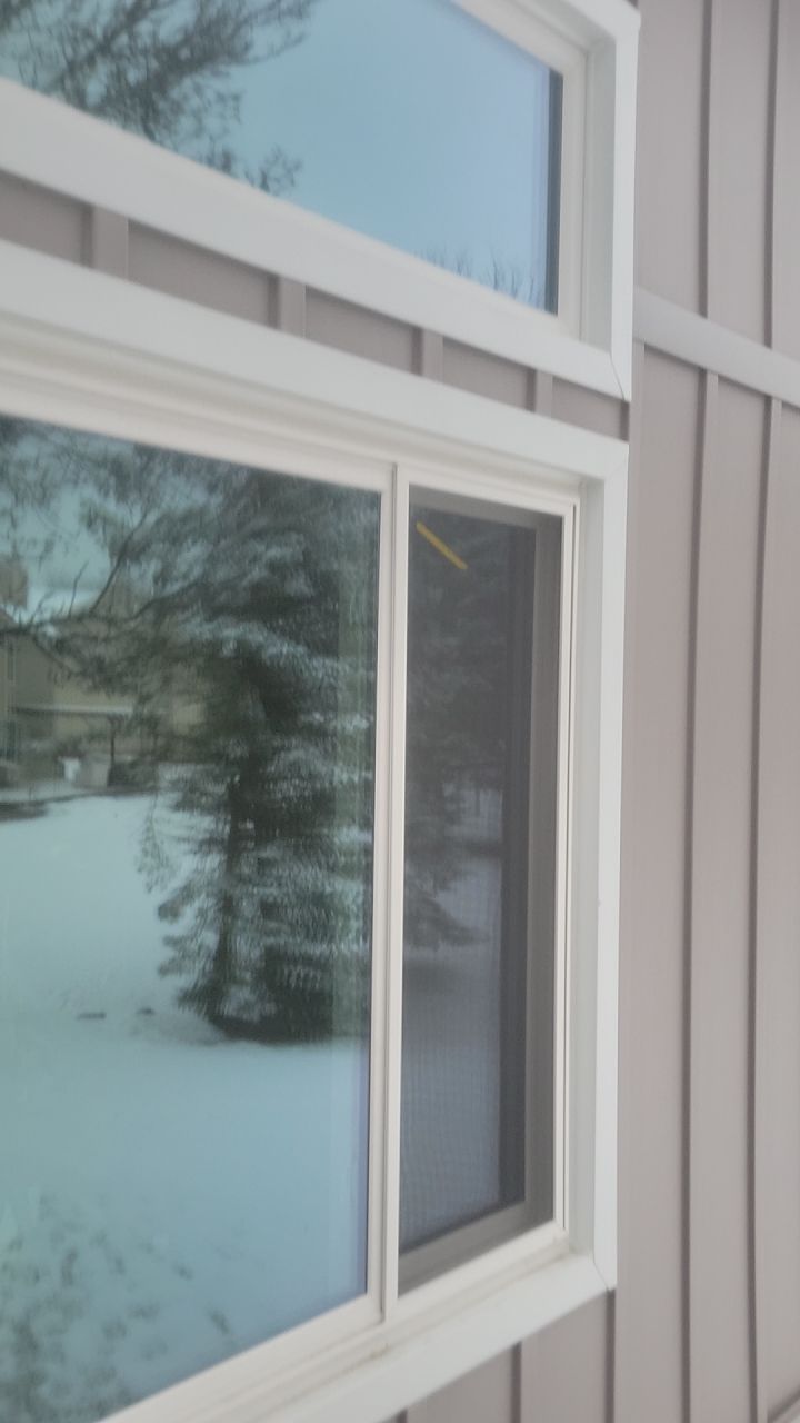 Snowy landscape seen through a white-framed window on a house exterior