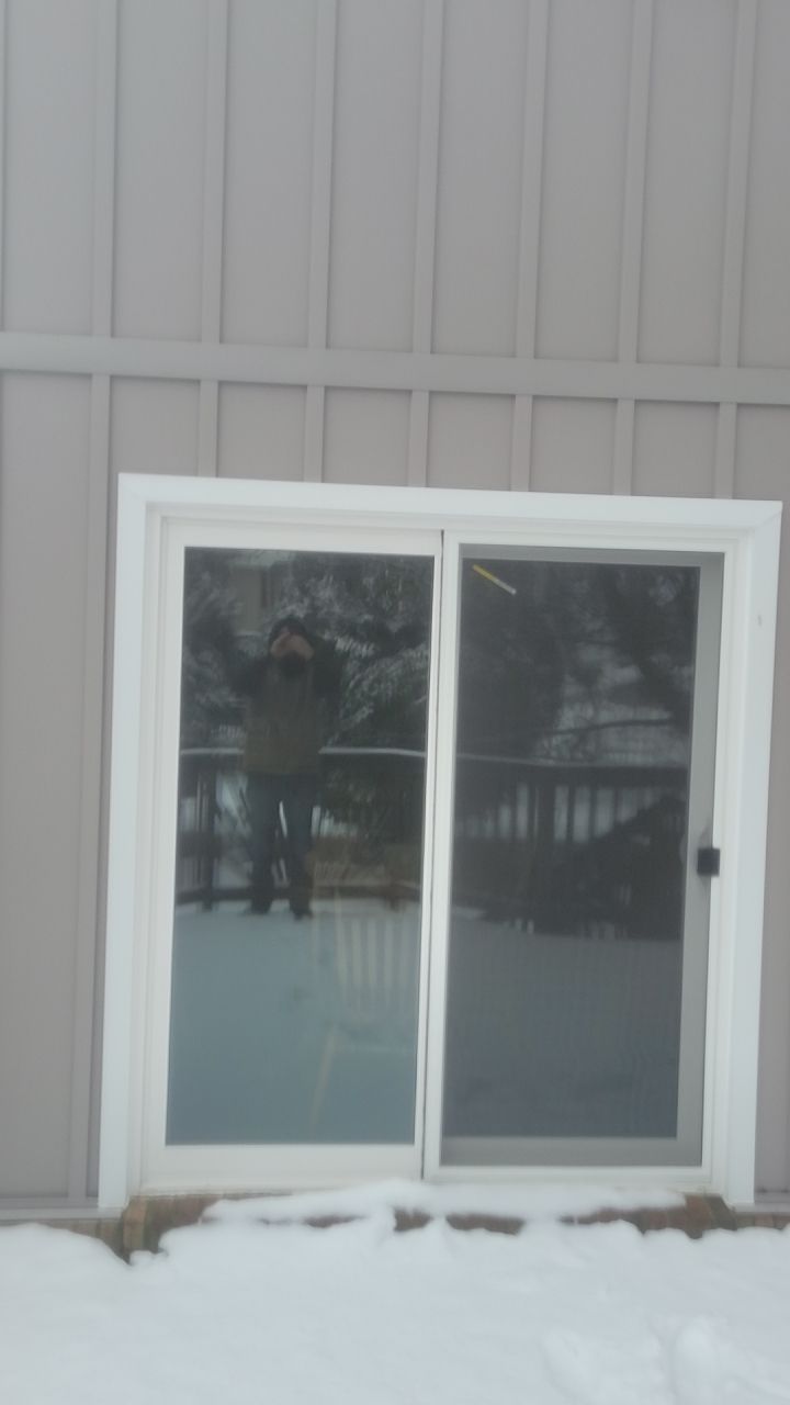 White sliding glass door on a gray building with snow on the ground.