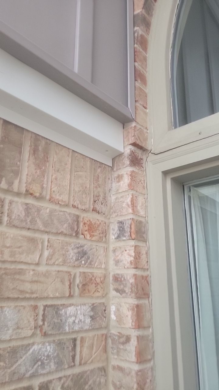 Close-up of a brick exterior wall and arched window trim on a house corner