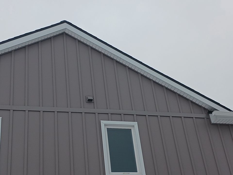 Gray house gable with vertical siding and a small window beneath the roofline