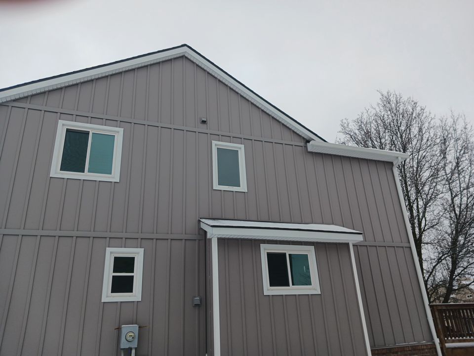 Gray two-story house with white trim and windows under an overcast sky