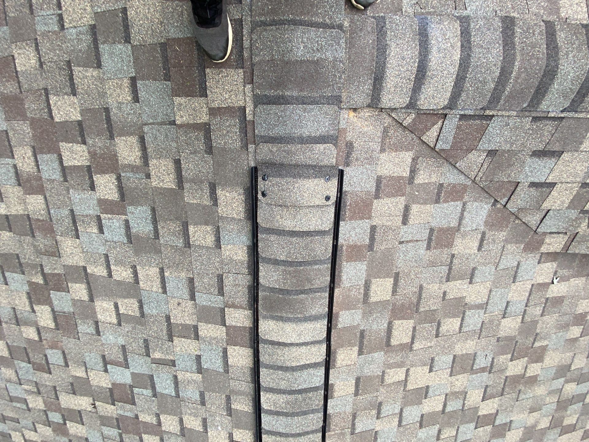 Roof shingles with a vertical ladder or vent opening near the ridge line.