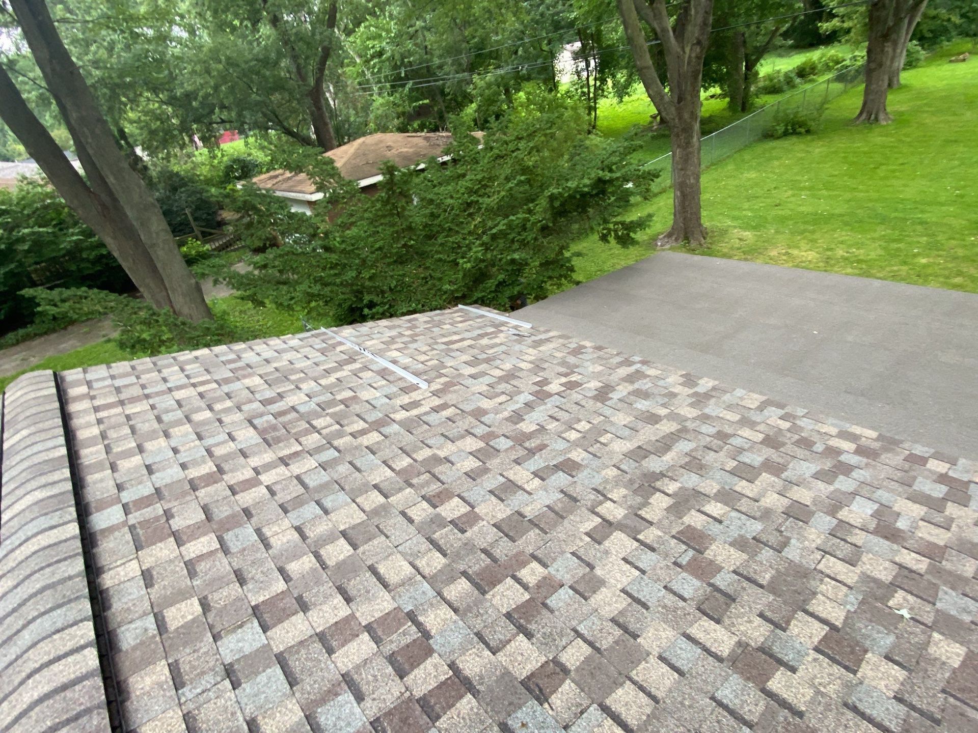 Stone patio overlooking a green yard with trees and a concrete walkway