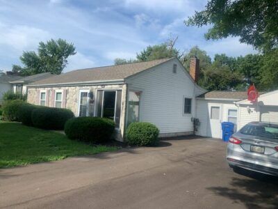 Single-story house with driveway, garage, and parked car under a partly cloudy sky