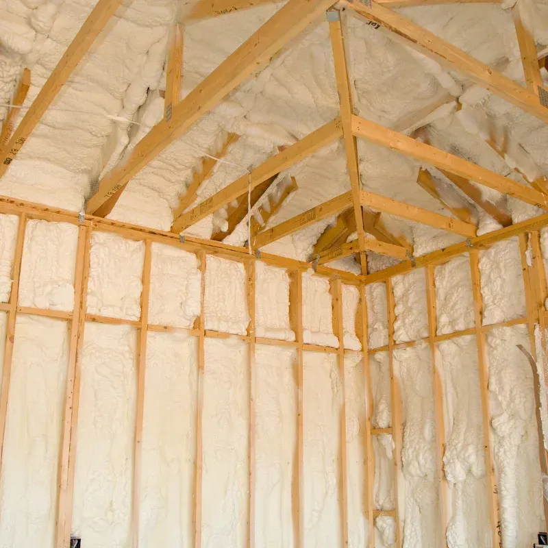 Insulated unfinished room with exposed wooden framing and white spray foam on walls and ceiling