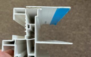 Cross-section of a white plastic profile with a blue strip, showing internal channels and grooves