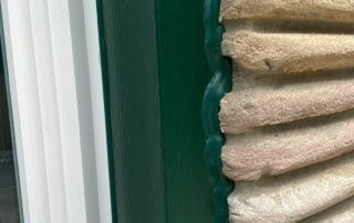 Close-up of beige folded towels stacked beside a green wall and white trim