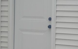 White front door with two blue knobs beside white siding