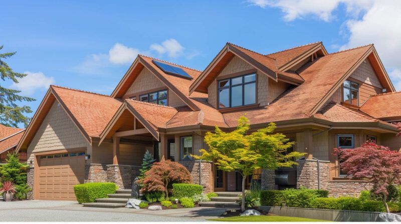 Large modern house with red shingle roof, stone facade, and landscaped front yard under a blue sky