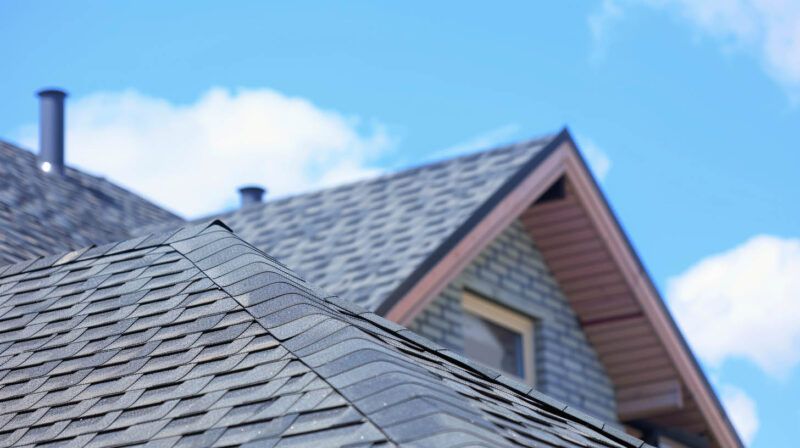 Slate rooftops with a gabled house roof against a blue sky