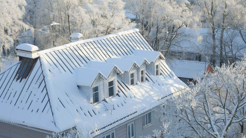 Snow-covered house roof with dormer windows in a winter landscape