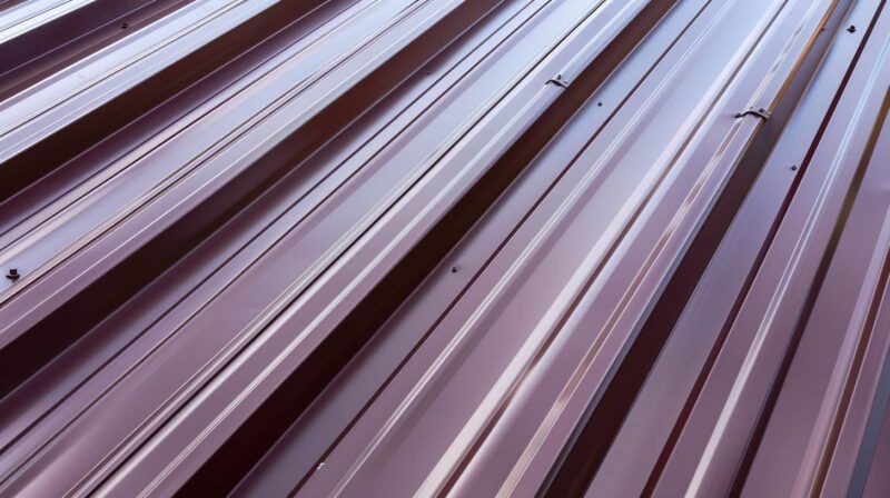 Close-up of corrugated metal roof panels in light gray and purple tones