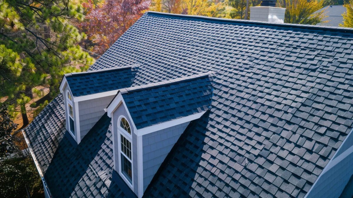 Shingled roof with dormer windows beside colorful autumn trees