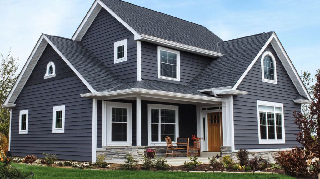 Gray two-story house with white trim, front porch, and dormer windows under a cloudy sky
