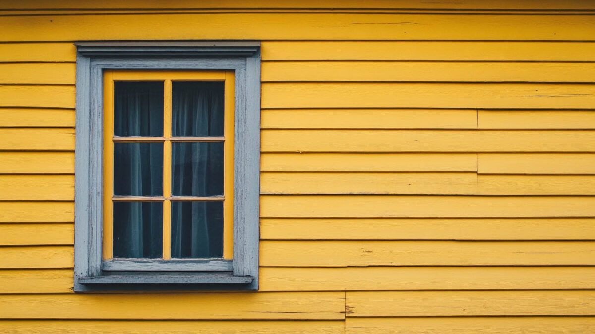 Blue-framed window on a yellow wooden wall