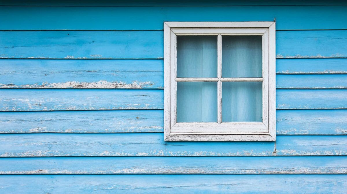 White-framed window on a weathered blue wooden wall